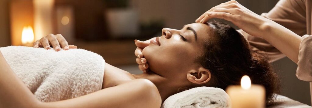 Attractive girl enjoying face massage in spa salon.